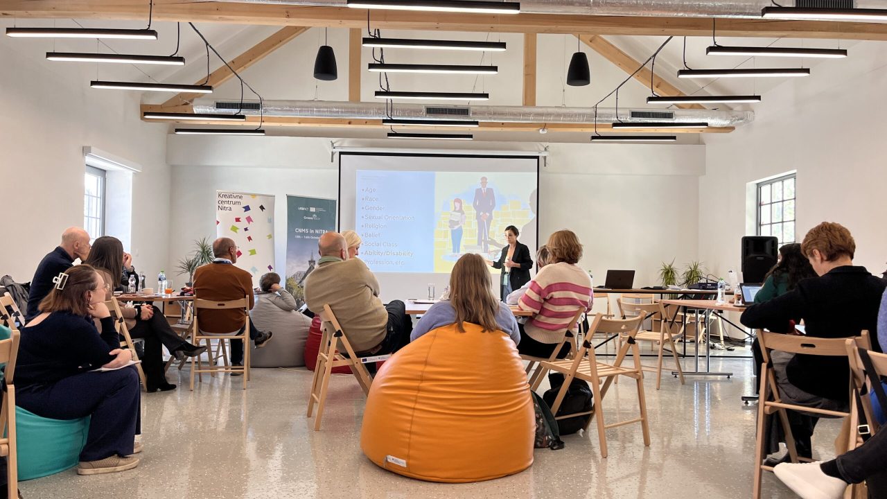 Iris presenting in front of the people sitting on beanbags and chairs.